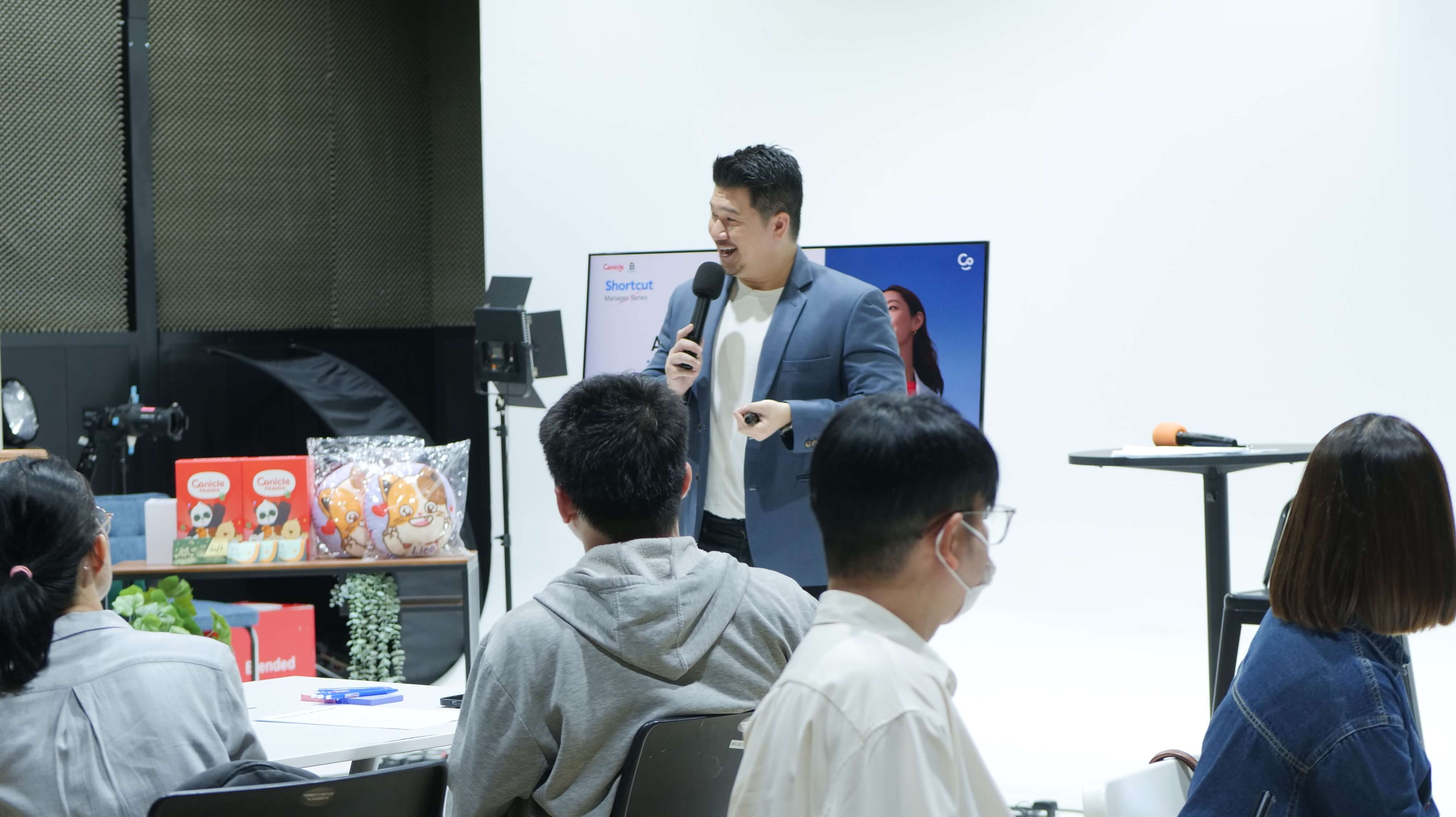 วิทยากรกำลังยืนพูดบรรยายในเวิร์กช็อป โดยมีผู้เข้าร่วมนั่งฟังอยู่