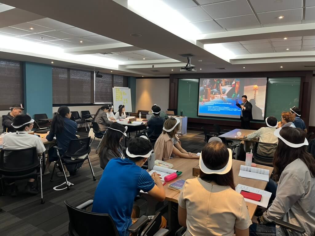 ผู้เข้าร่วมเวิร์กช็อปทุกคนสวมที่คาดศีรษะสีขาวขณะนั่งฟังวิทยากรบรรยายในเวิร์กช็อป โดยมีผู้เข้าร่วมนั่งฟังอยู่